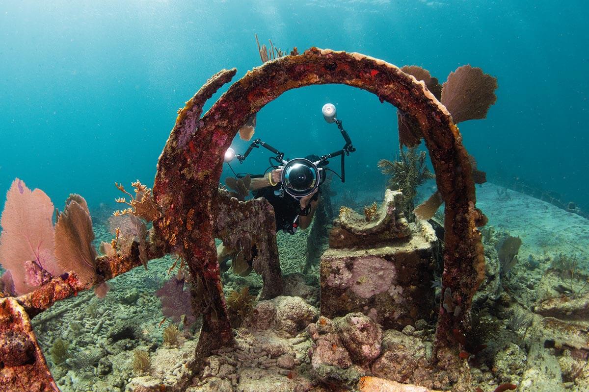 a diver with a camera looking through a ring of steel on the wreck of the City of Washington in the Florida Keys