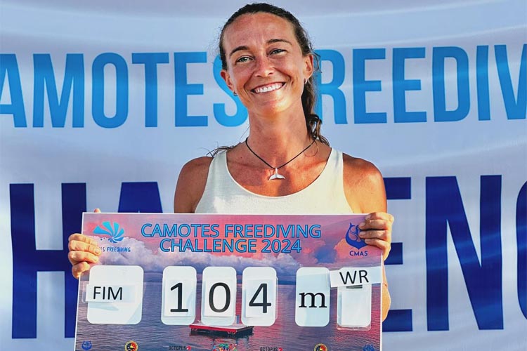 a picture of freediver alessia zecchini holding her 104m world record sign