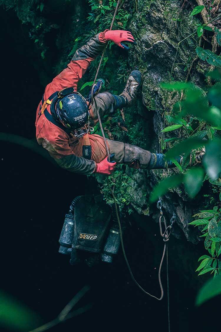 cave diver lowering himself into cave with rebreather