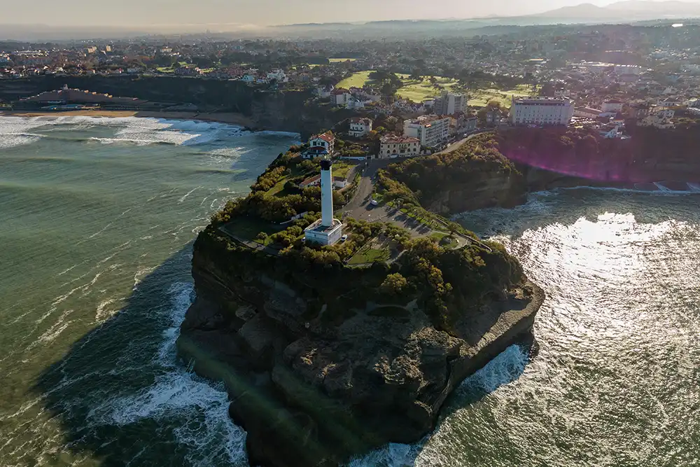 an aerial view of the biarrtiz lighthouse and the cliffs underneath it