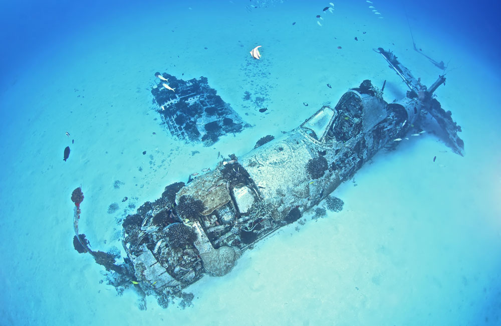 the wreck of WW11 Corsair partially buried in the sand on the seafloor