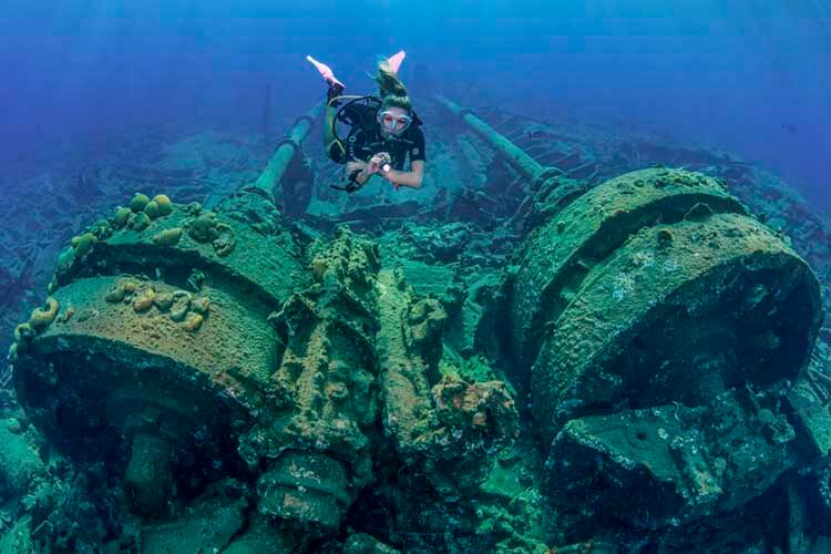 a diver swimming over the two huge boilers of bermuda's Cristóbal Colón wreck
