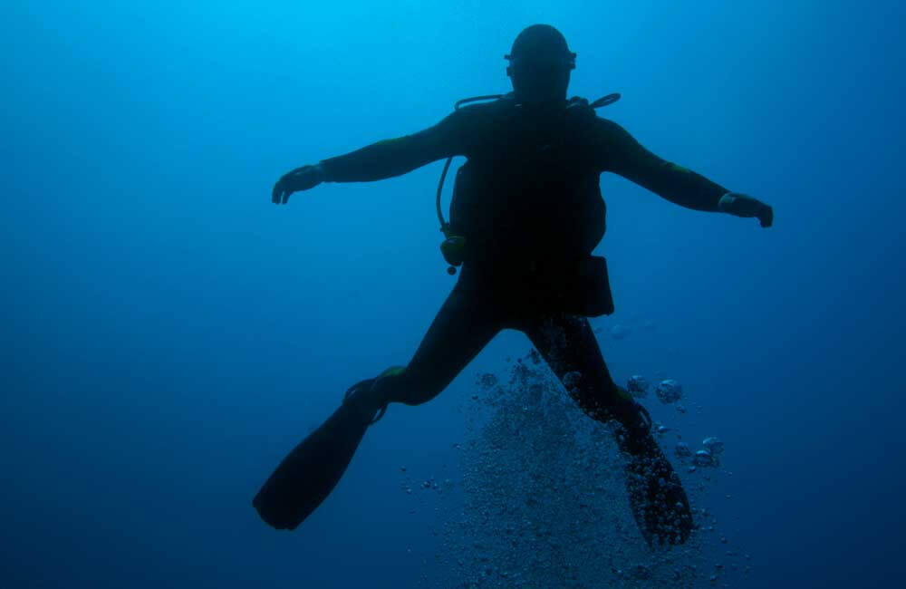 silhoutte of drift diving diver