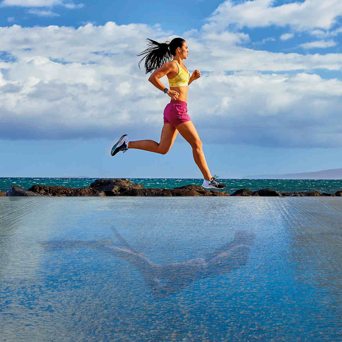 woman running alongside water with a reflection of scuba diver