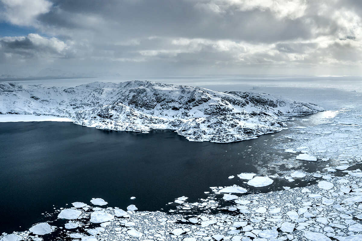 An aerial view of the water and icy mountains of greenland