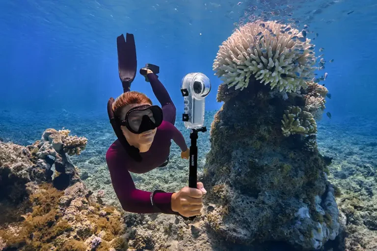 freediver swimming underwater near coral with an insta360 x4 camera