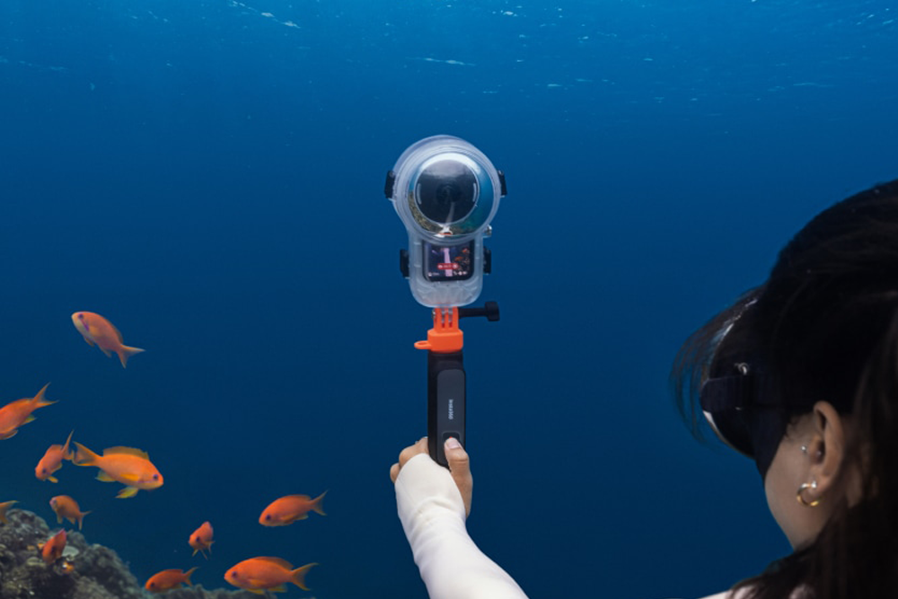 Diver using the Insta360 Underwater Selfie Stick with Remote and a camera in a dive housing