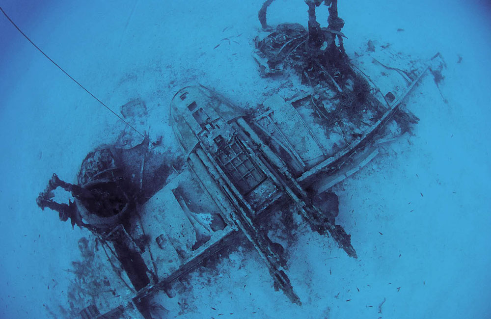 The remains of a Bristol Beua fighter rests upside down on white sand off Malta