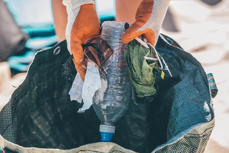 handful of beach litter being deposited into a cleanup bag