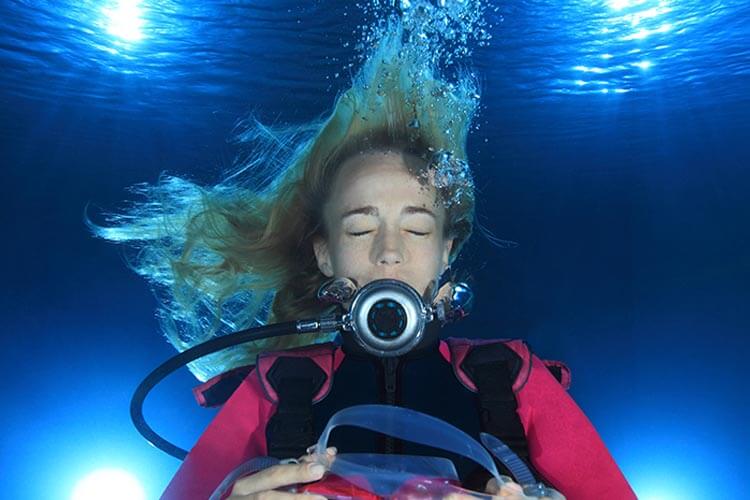 woman in a pool wearing scuba gear without a mask