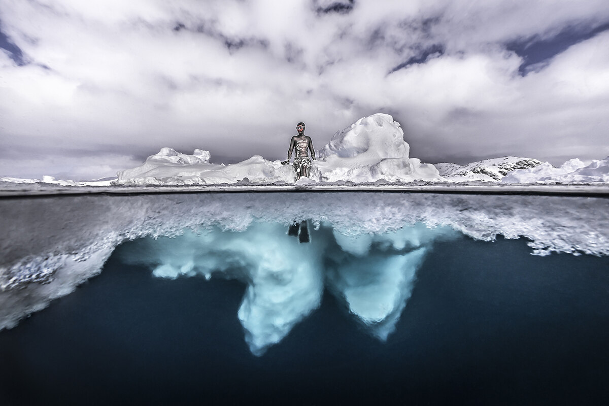 A photo of both above the ice and below the ice in the middle a person is sitting