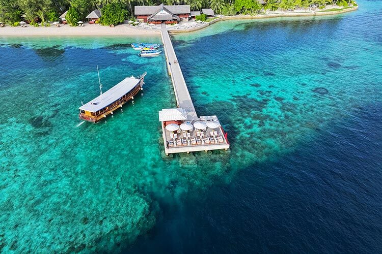 aerial overview of wakatobi dive boat approaching the resort's jetty