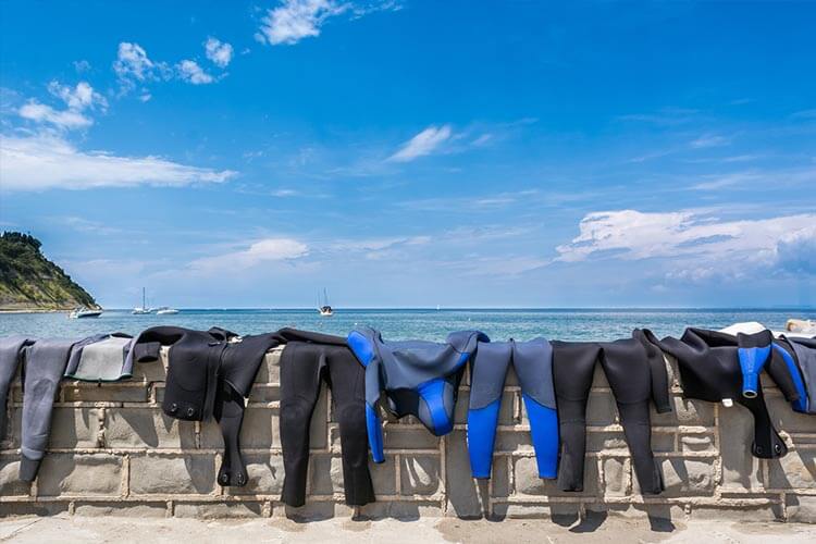 wetsuits hanging on a wall in the sun